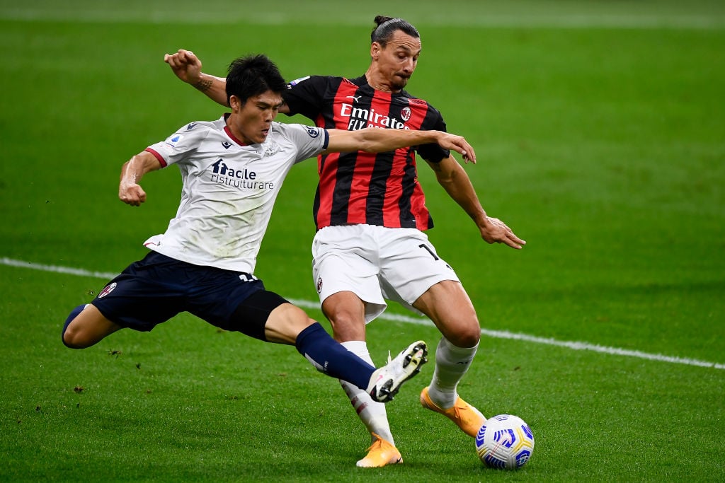 Zlatan Ibrahimovic (R) of AC Milan is tackled by Takehiro