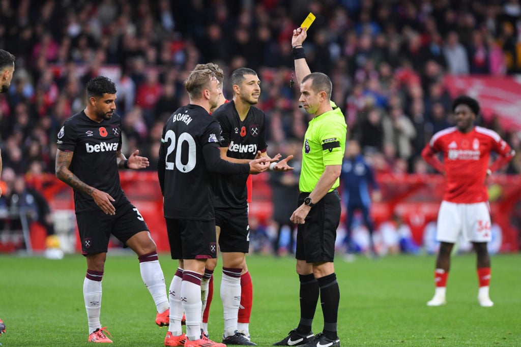 Referee Peter Bankes shows a yellow card to Guido Rodriguez of West Ham United during the Premier League match between Nottingham Forest and West H...