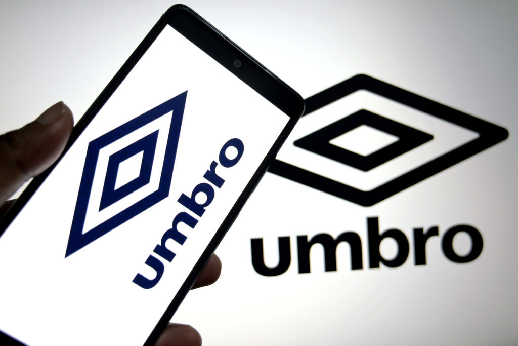 In this photo illustration, an Umbro Logo is seen displayed