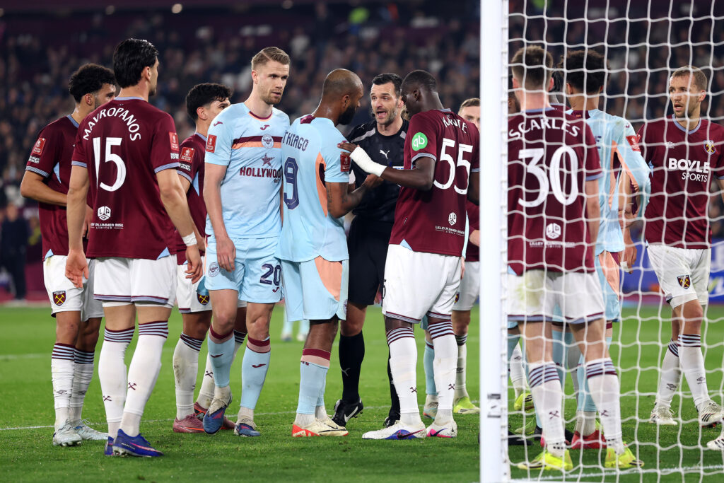 Referee Andy Madley speaks to Igor Thiago of Brentford and Mohamadou Kante of West Ham