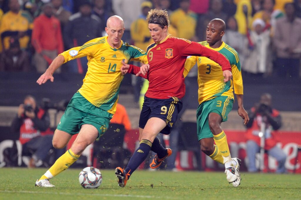 Matthew Booth of South Africa up against Spain's Fernando Torres - Children's Football In South African Townships